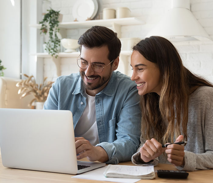 Happy young couple paying bills online in computer app